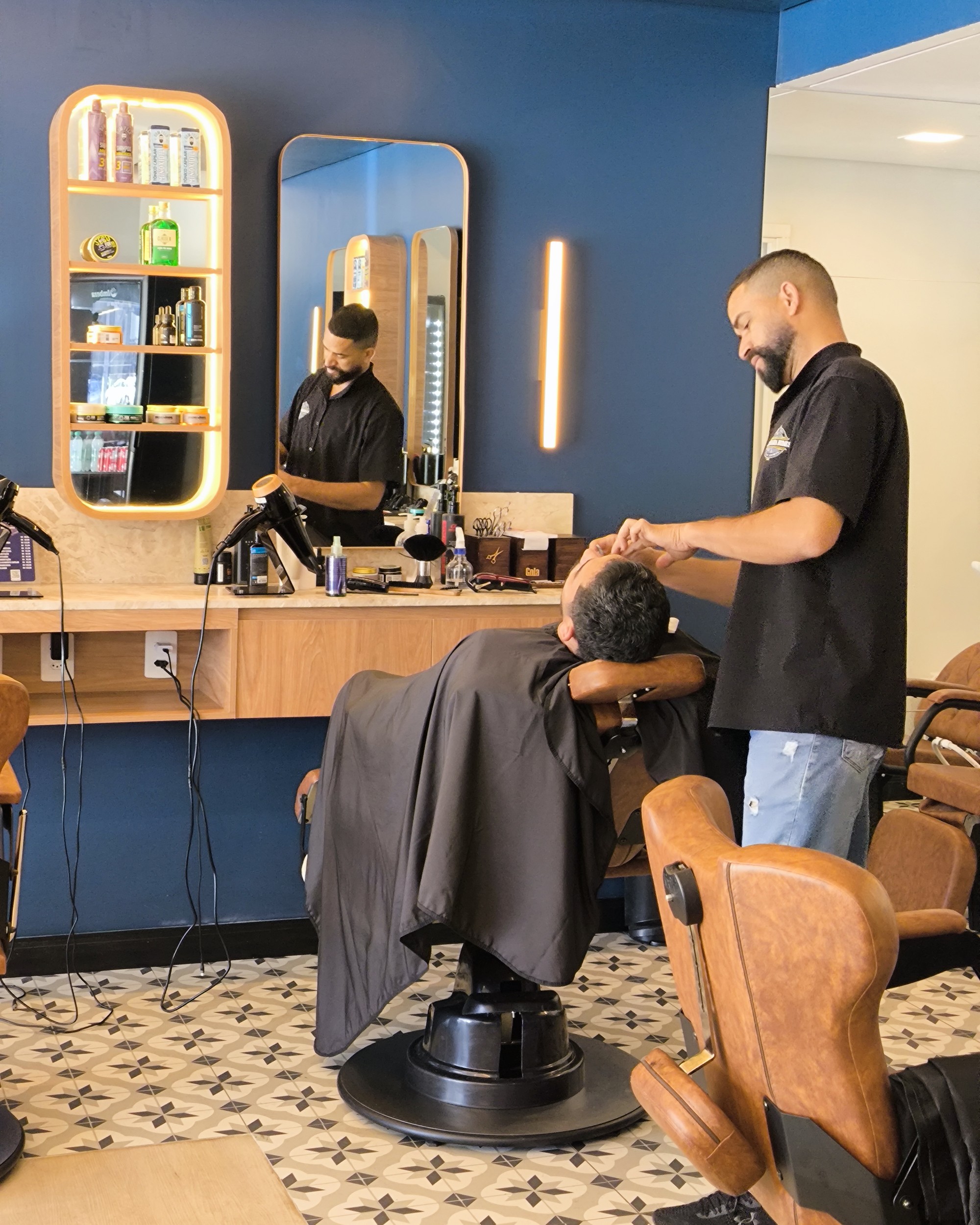 Barbeiro fazendo a barba de um cliente reclinado na poltrona