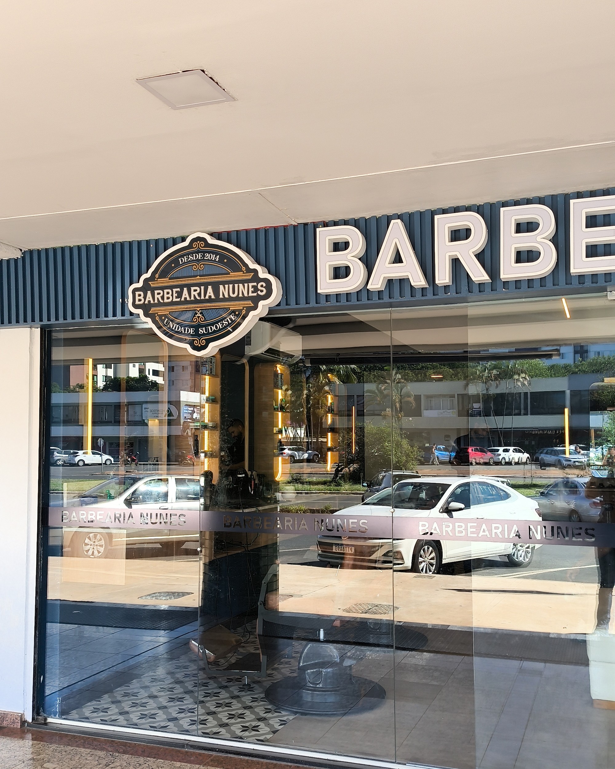 Fachada da barbearia vista em ângulo, com o emblema da unidade Sudoeste