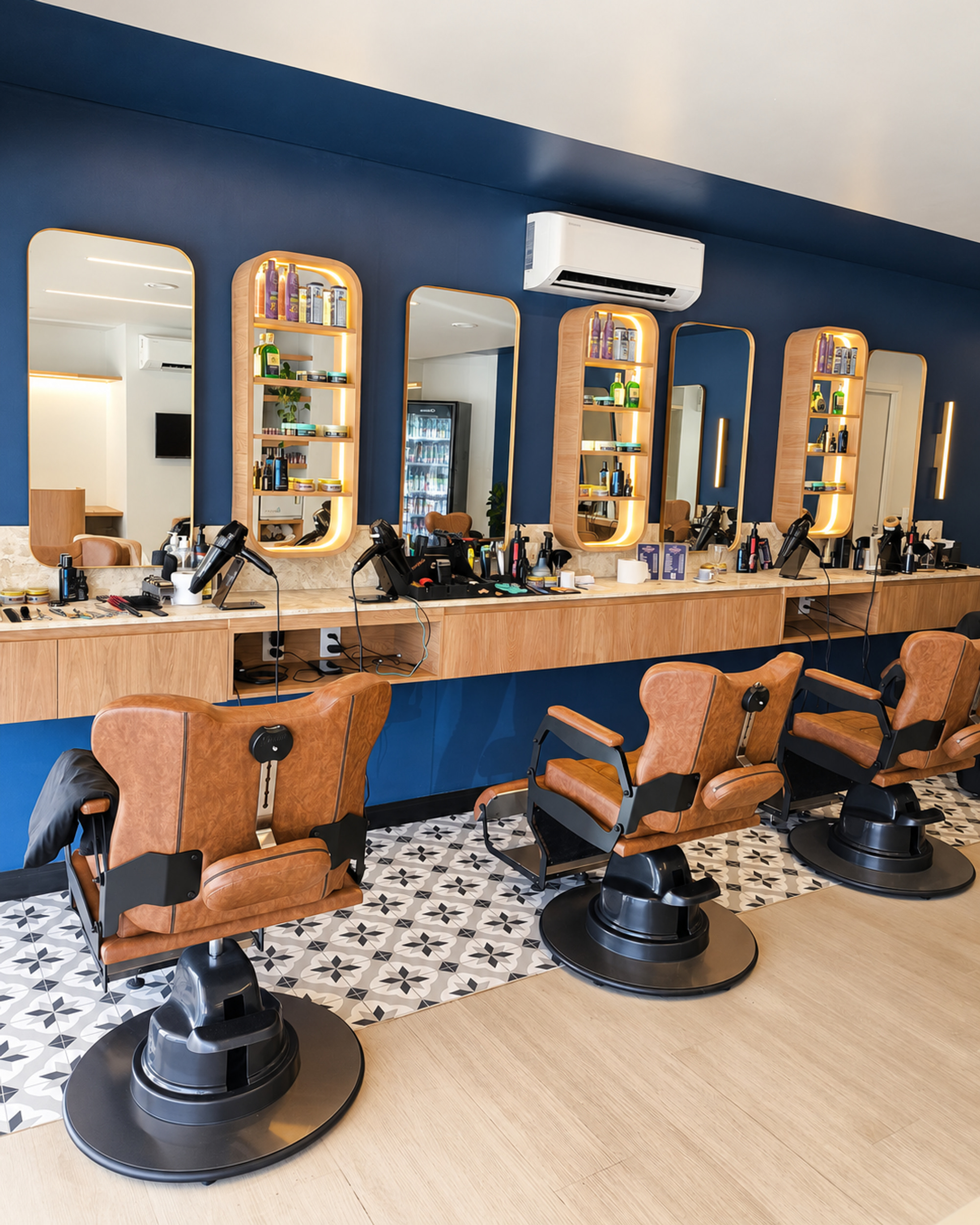 Salão da Barbearia Nunes Sudoeste com parede azul-marinho, espelhos arredondados, nichos iluminados e poltronas de couro